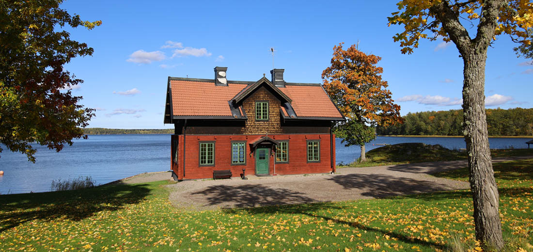 Brygghuset är en röd stuga vid sjön att hyra. Fjällpanel och spröjsade fönster