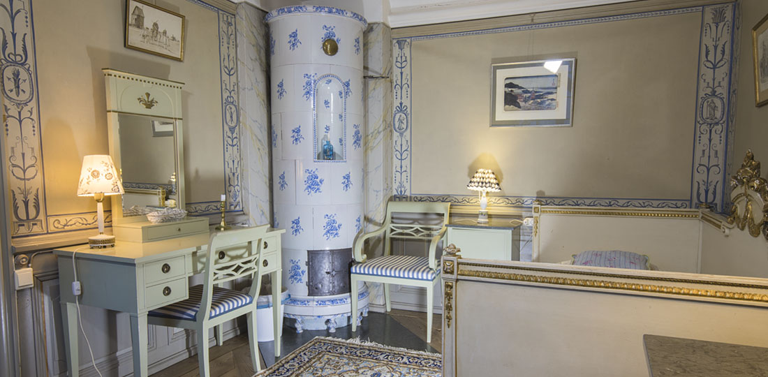 Lilla blå gästrummet med blå kakelugn och väggmålningar