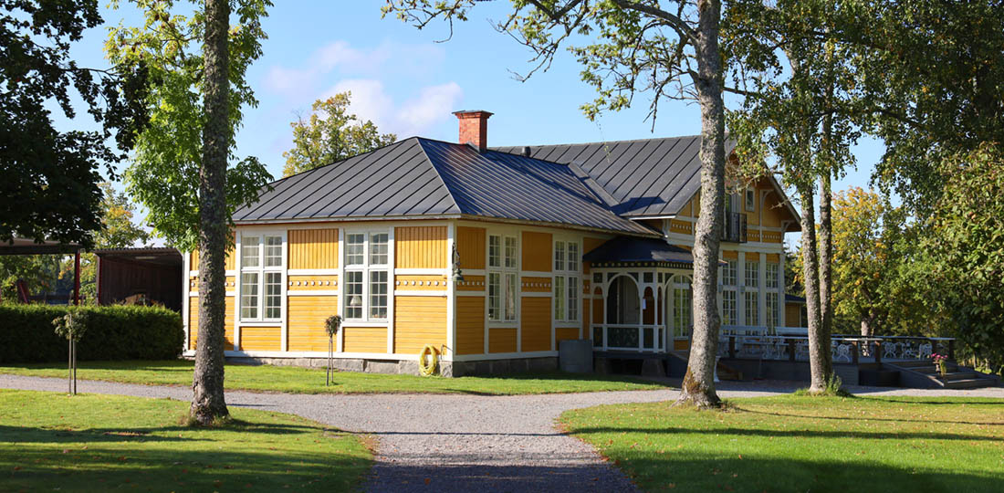 Gula paviljongen med gröna gräsmattor, ett gult hus med snickarglädje